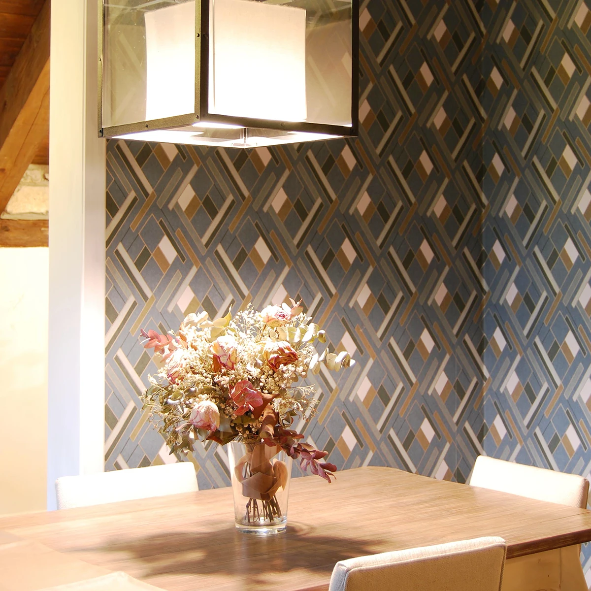 detalle de mesa de madera con centro floral sobre pared con papel de motivos geometricos