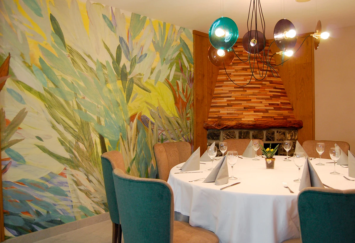 mesa de restaurante con chimenea y mural de hojas de fondo