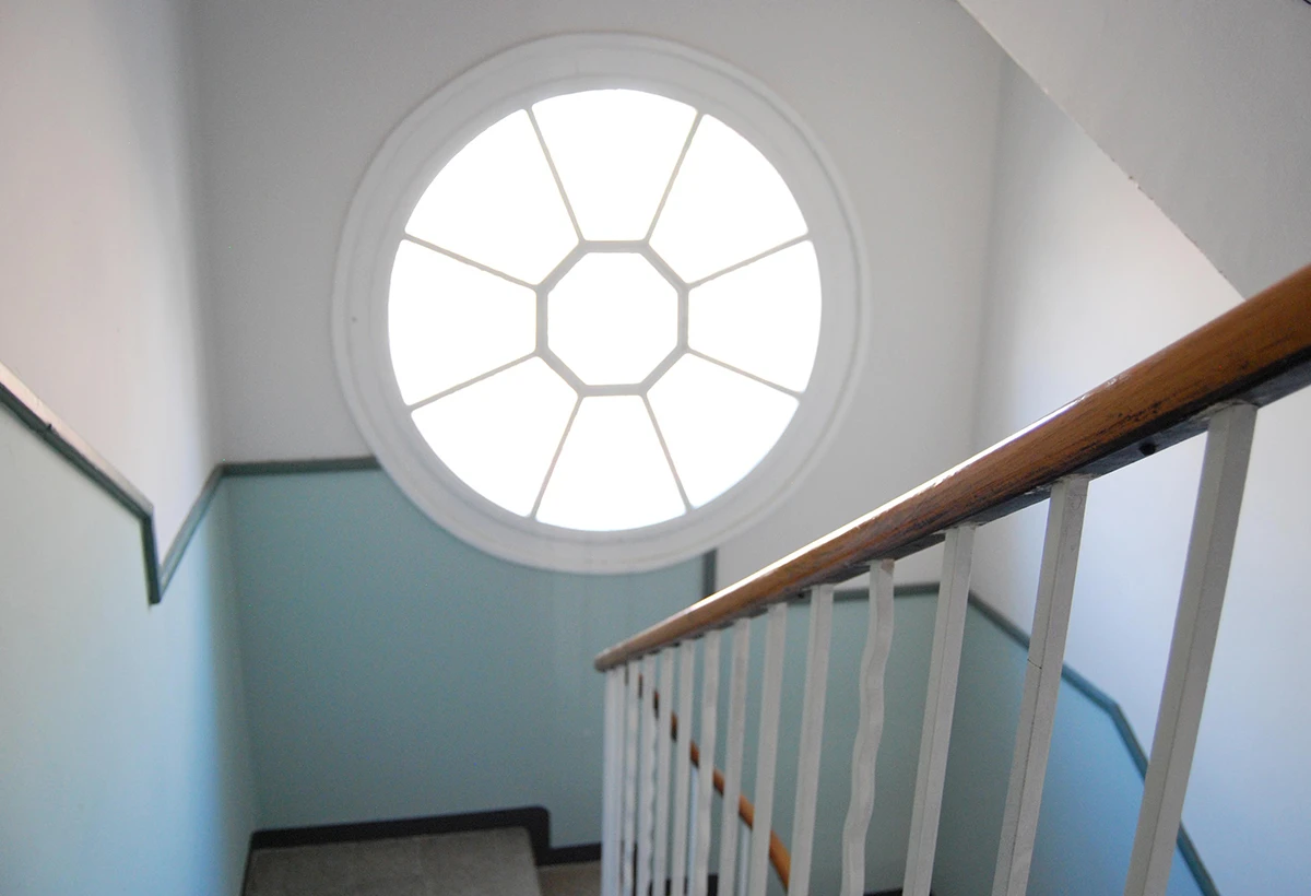 detalle de barandilla de escalera con ventana circular en la pared