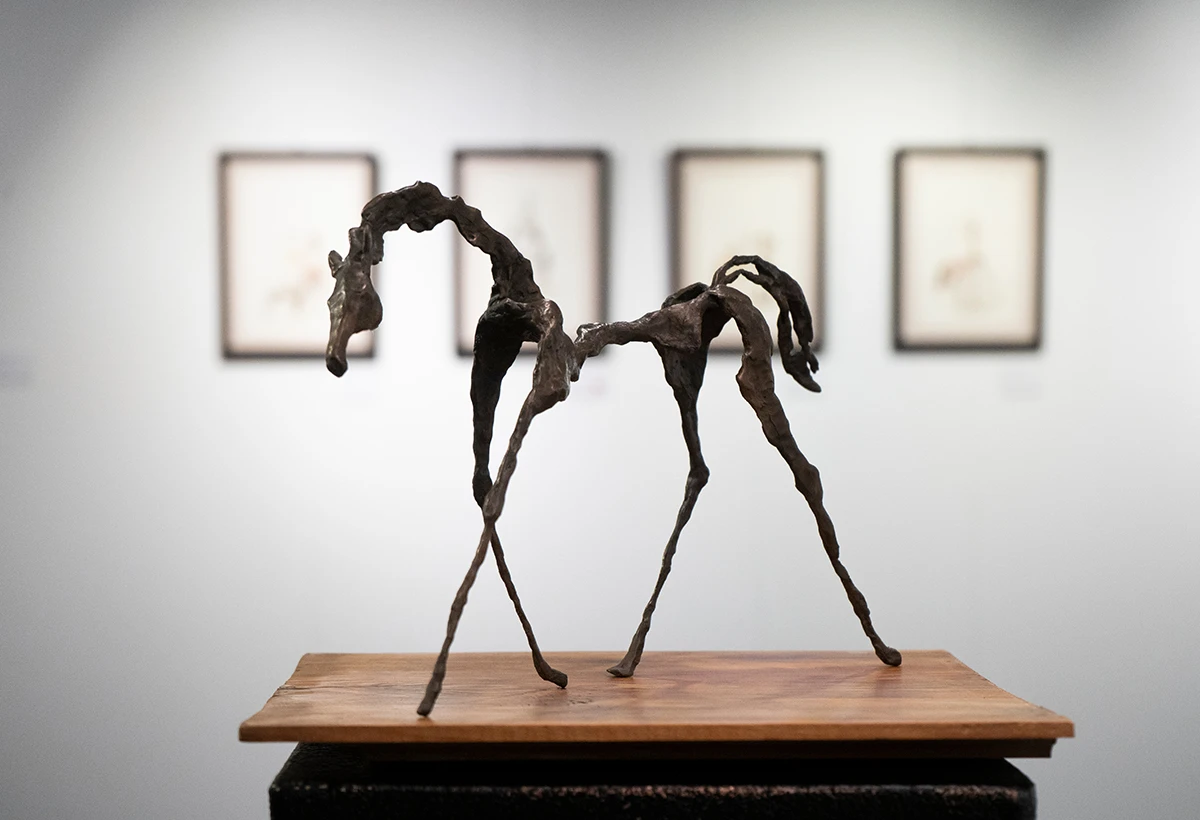 escultura en metal de caballo sobre peana y fondo de museo