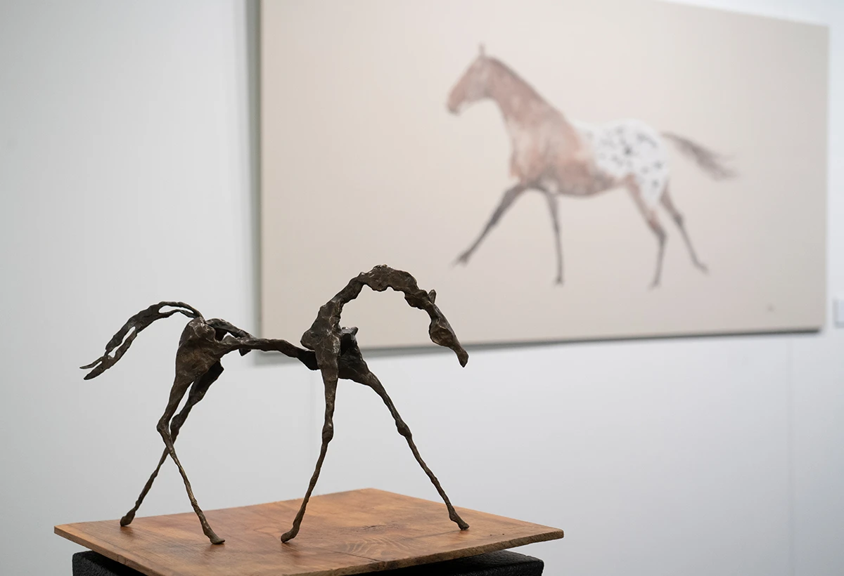 escultura en metal de caballo sobre peana y fondo de museo